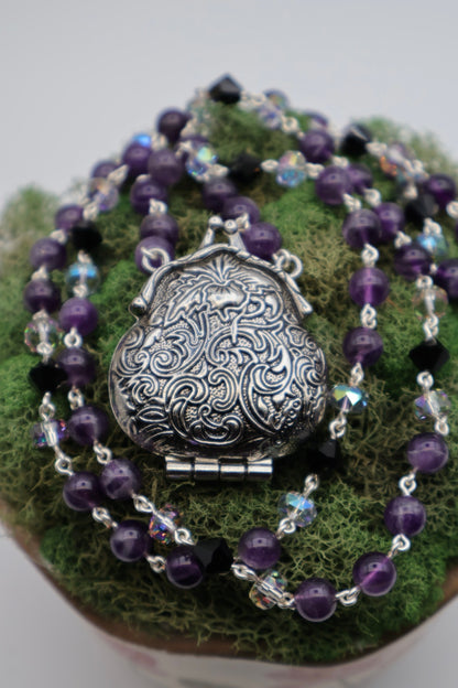 Purple beaded necklace with a silver pendant on a green surface