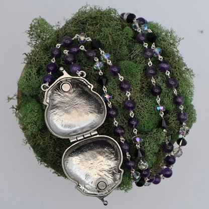 Necklace with silver locket and purple beads on a moss background