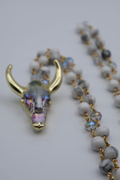 Necklace with a bull skull pendant and white beads on a light gray background