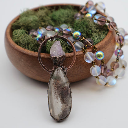 Necklace with a pendant in front of a wooden bowl with moss