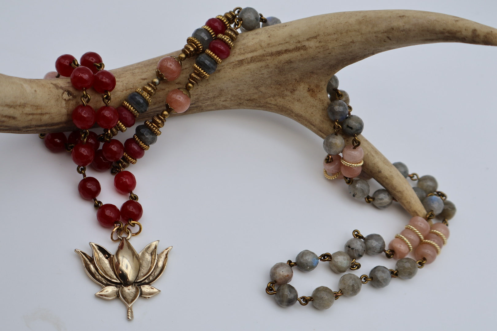 Two beaded necklaces with a gold lotus pendant on a white background