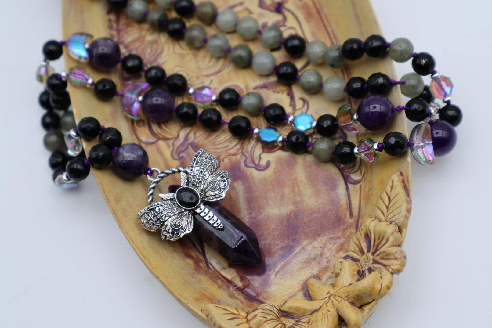 Necklace with beads and a dragonfly pendant on a decorative wooden surface