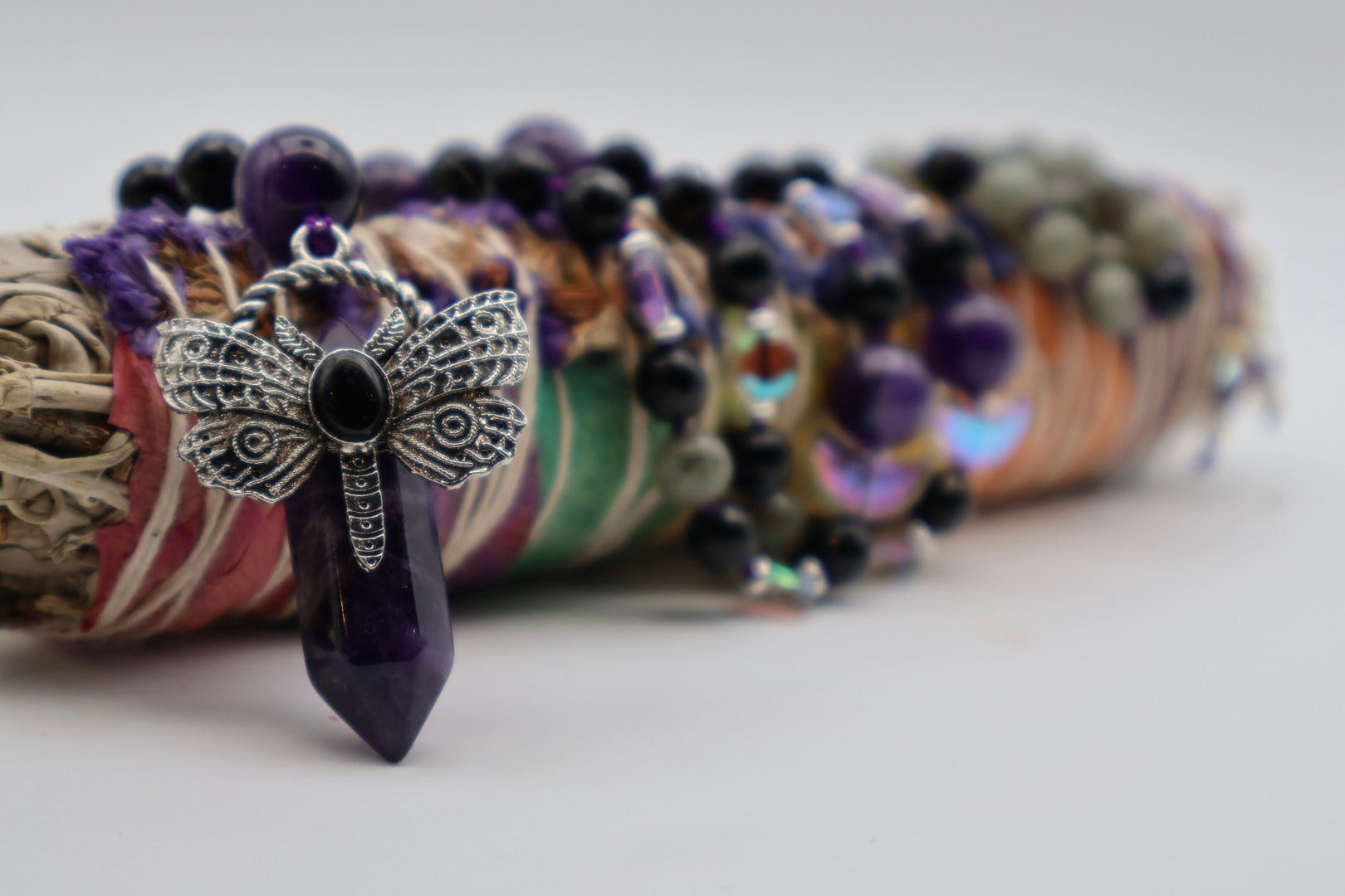 Bracelets with dragonfly charm and amethyst stone on a white background