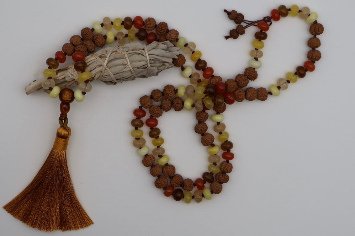 Beaded necklace with tassel and sage on a white background