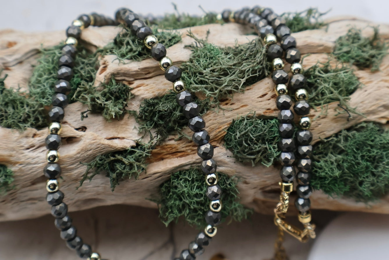 Two beaded necklaces on a piece of wood with moss