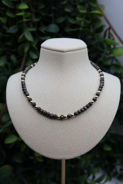 Necklace on a mannequin bust with a green leafy background