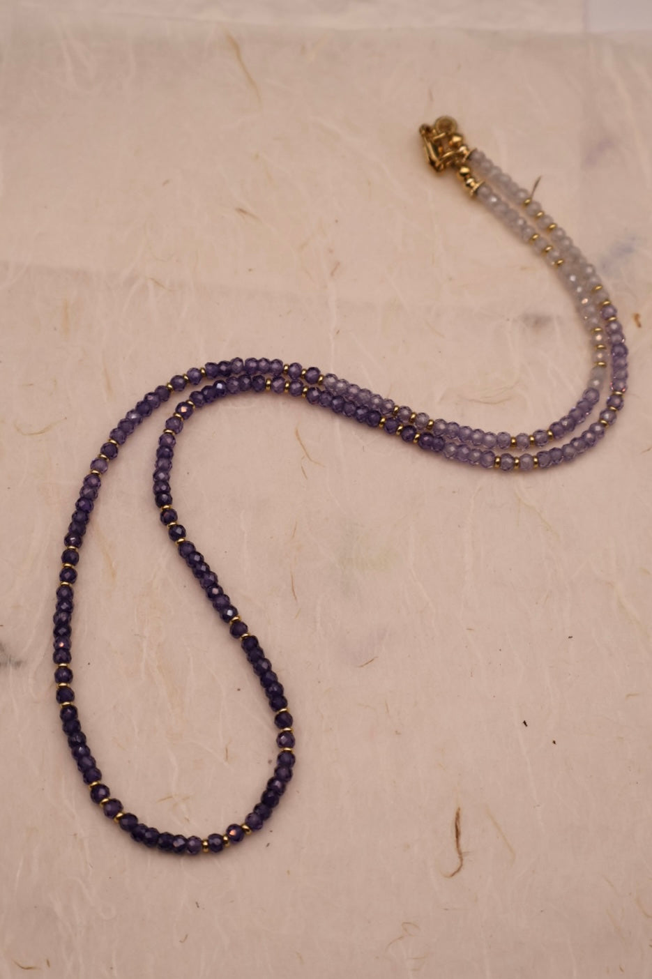 Beaded necklace with a gold clasp on a light beige surface