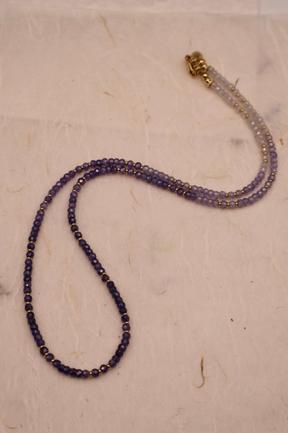 Beaded necklace with a gold clasp on a light beige surface