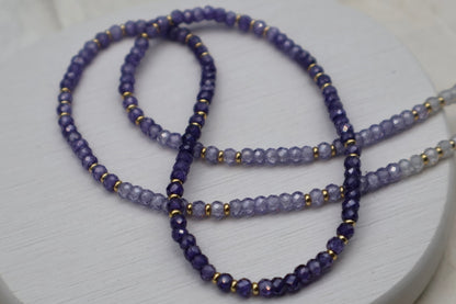 Purple beaded necklace on a white surface