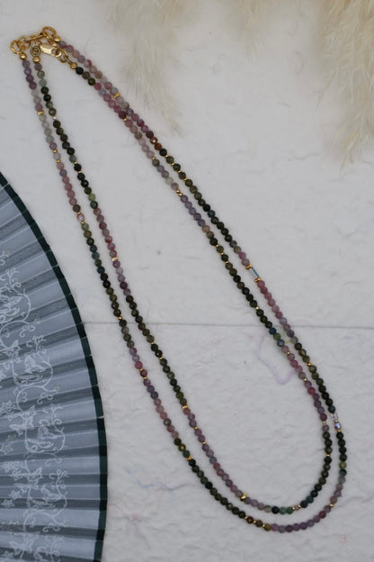 Multicolored beaded necklace with a gold clasp on a textured surface