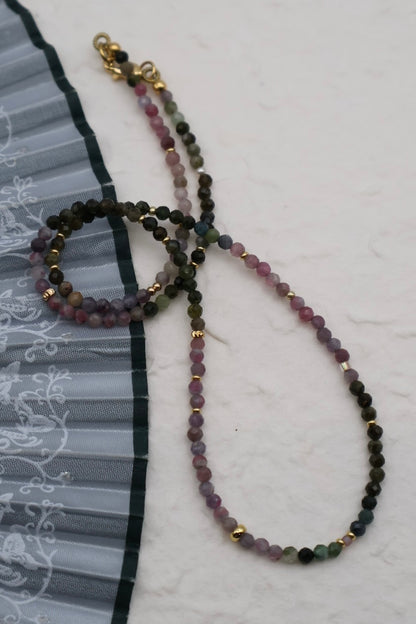 Multicolored beaded necklace with gold accents on a white background