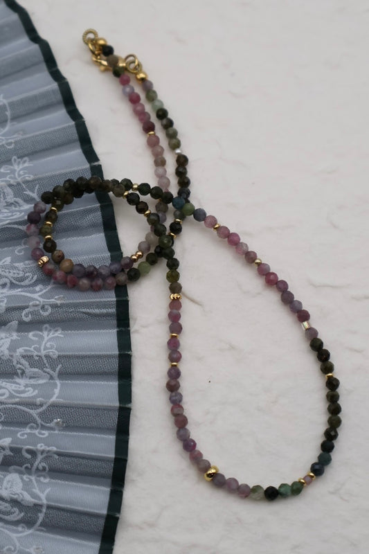 Multicolored beaded necklace with gold accents on a white background