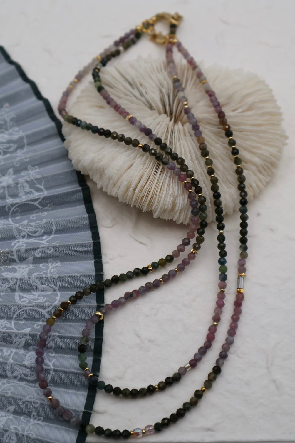 Beaded necklace with a textured white ball on a light gray background