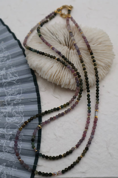 Beaded necklace with a textured white ball on a light gray background