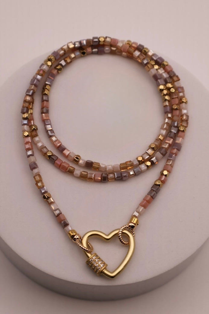 Beaded necklace with a gold heart-shaped clasp on a light gray background