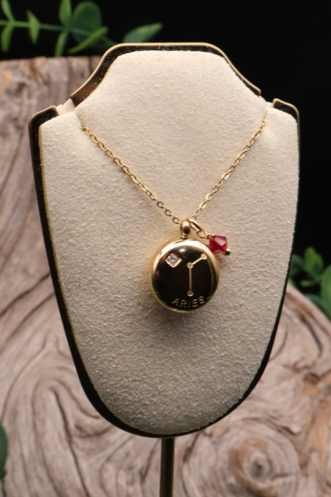 Gold necklace with a pendant on a white stand with a natural background