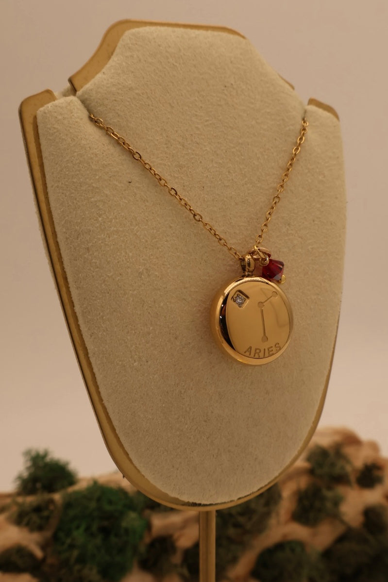 Gold necklace with a pendant on a beige bust against a blurred natural background