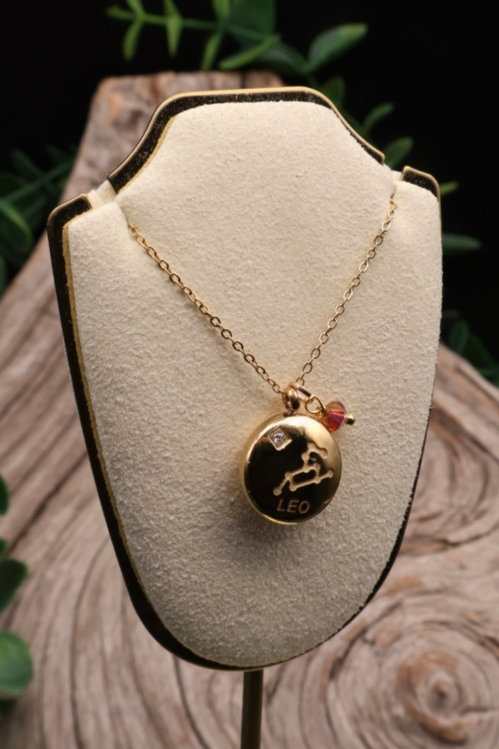 Gold necklace with a Leo zodiac pendant on a white cushioned stand.