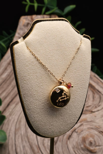 Gold necklace with a Leo zodiac pendant on a white cushioned stand.
