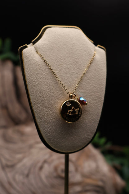 Gold necklace with a black pendant on a white bust against a dark background