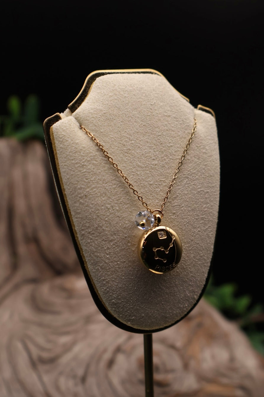 Gold necklace with a pendant on a beige display stand against a dark background