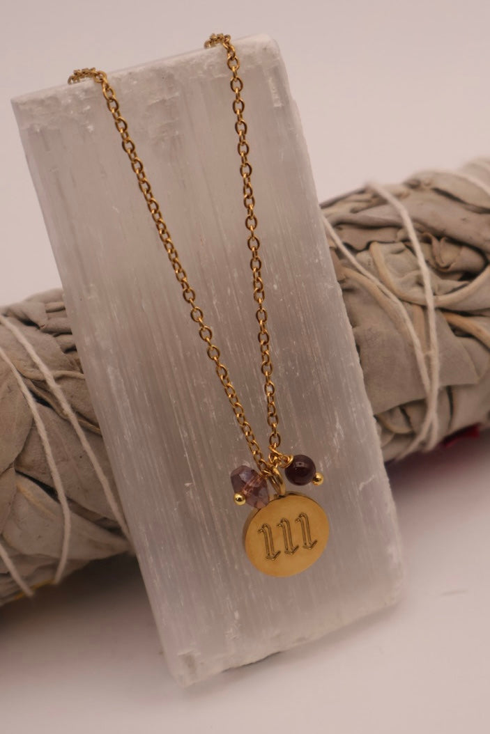 Gold necklace with a circular pendant and beads on a textured white surface