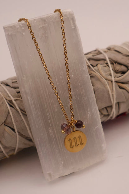 Gold necklace with a circular pendant and beads on a textured white surface
