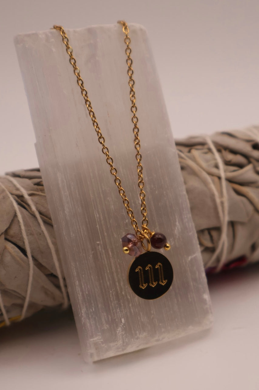 Necklace with a black pendant and gold chain on a white stone surface