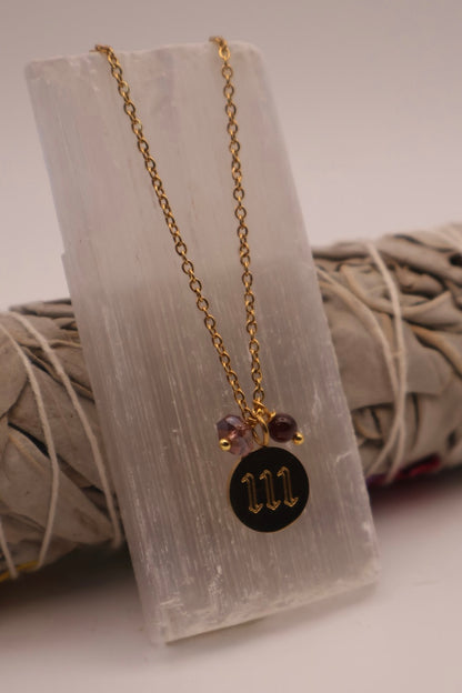 Necklace with a black pendant and gold chain on a white stone surface