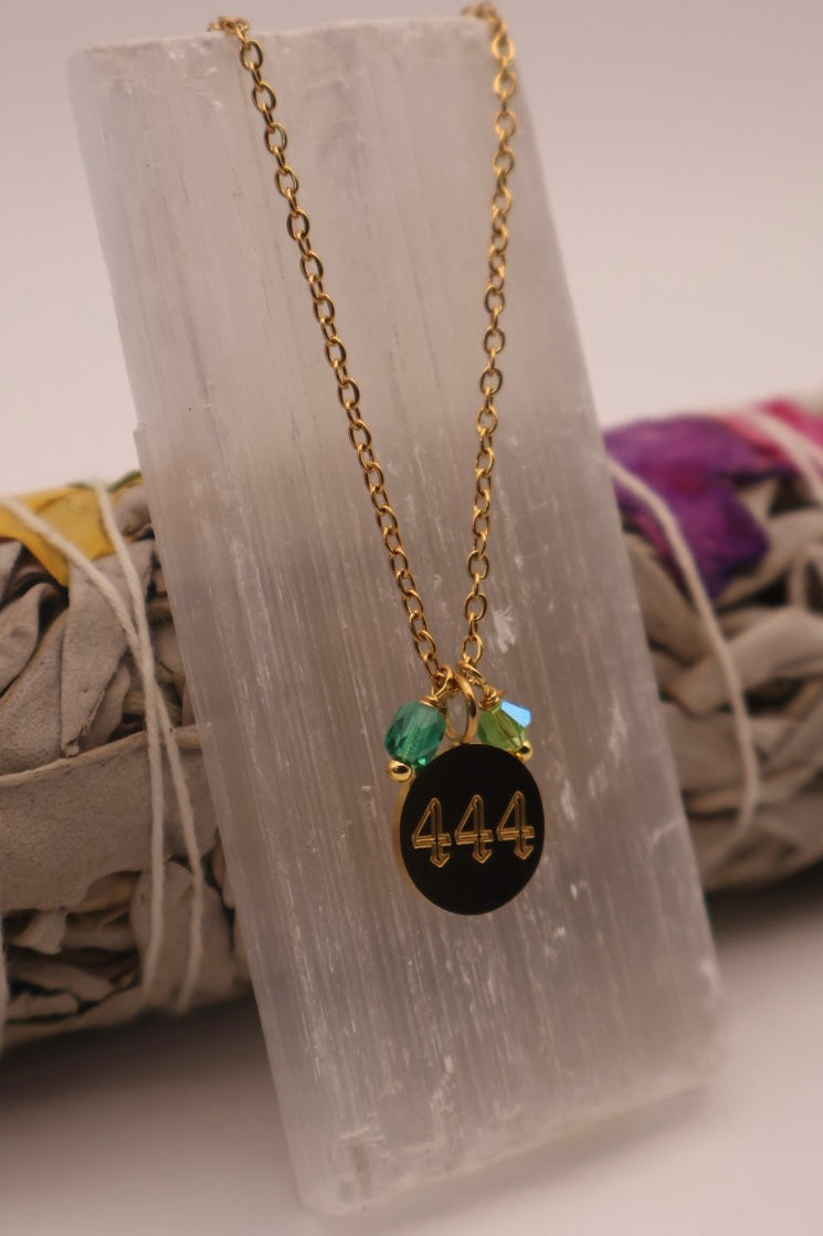 Necklace with a black pendant featuring the number 444 on a stone surface.