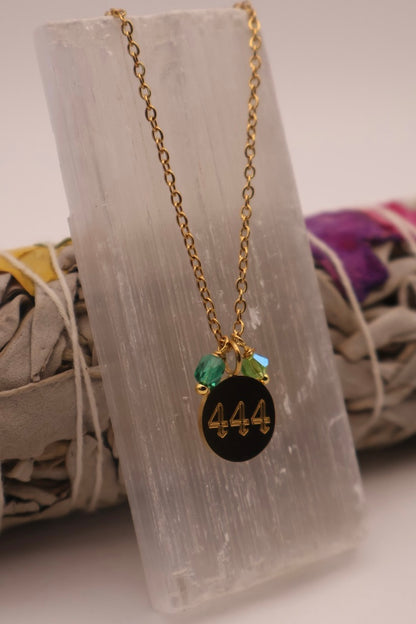Necklace with a black pendant featuring the number 444 on a stone surface.