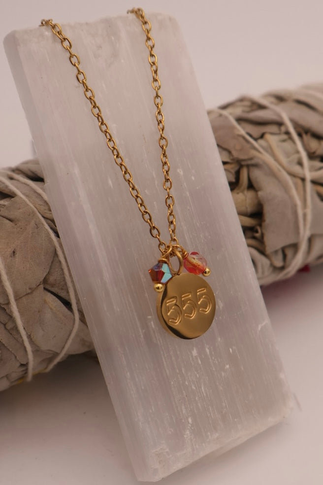 Gold necklace with a pendant on a white stone surface