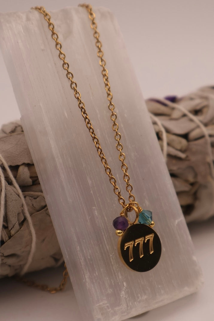 Necklace with a black pendant featuring the number 777 on a white fabric background