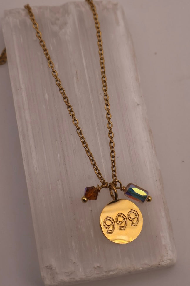 Gold necklace with a '999' pendant on a textured stone surface