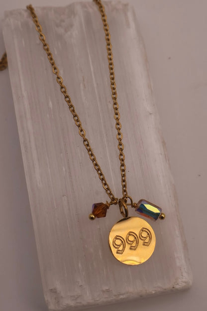 Gold necklace with a '999' pendant on a textured stone surface