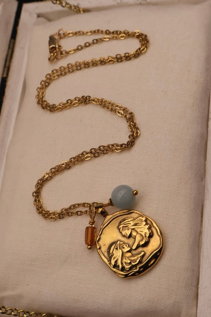 Gold necklace with a pendant in an open jewelry box on a dark background