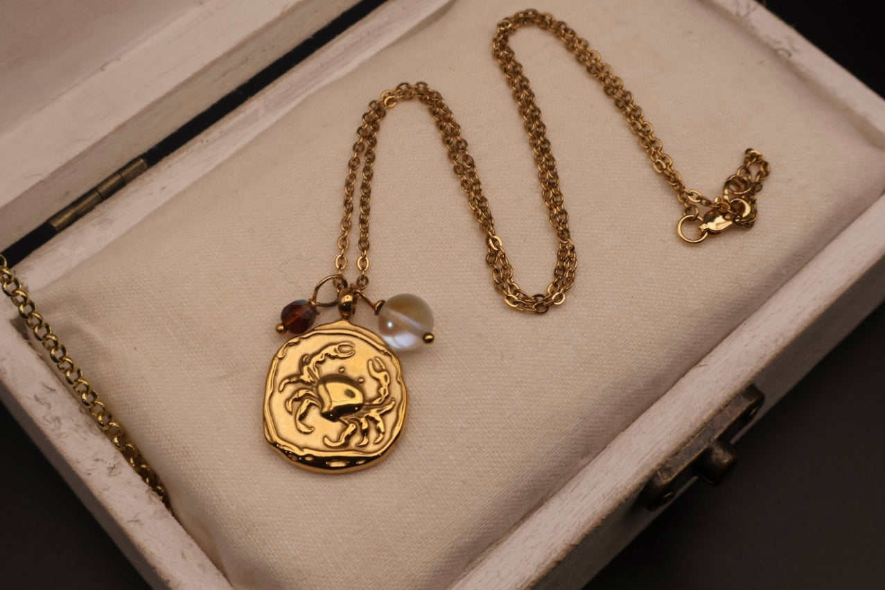 Gold necklace with a scorpion pendant on a textured surface