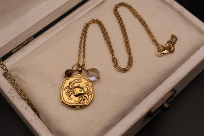 Gold necklace with a scorpion pendant on a textured surface