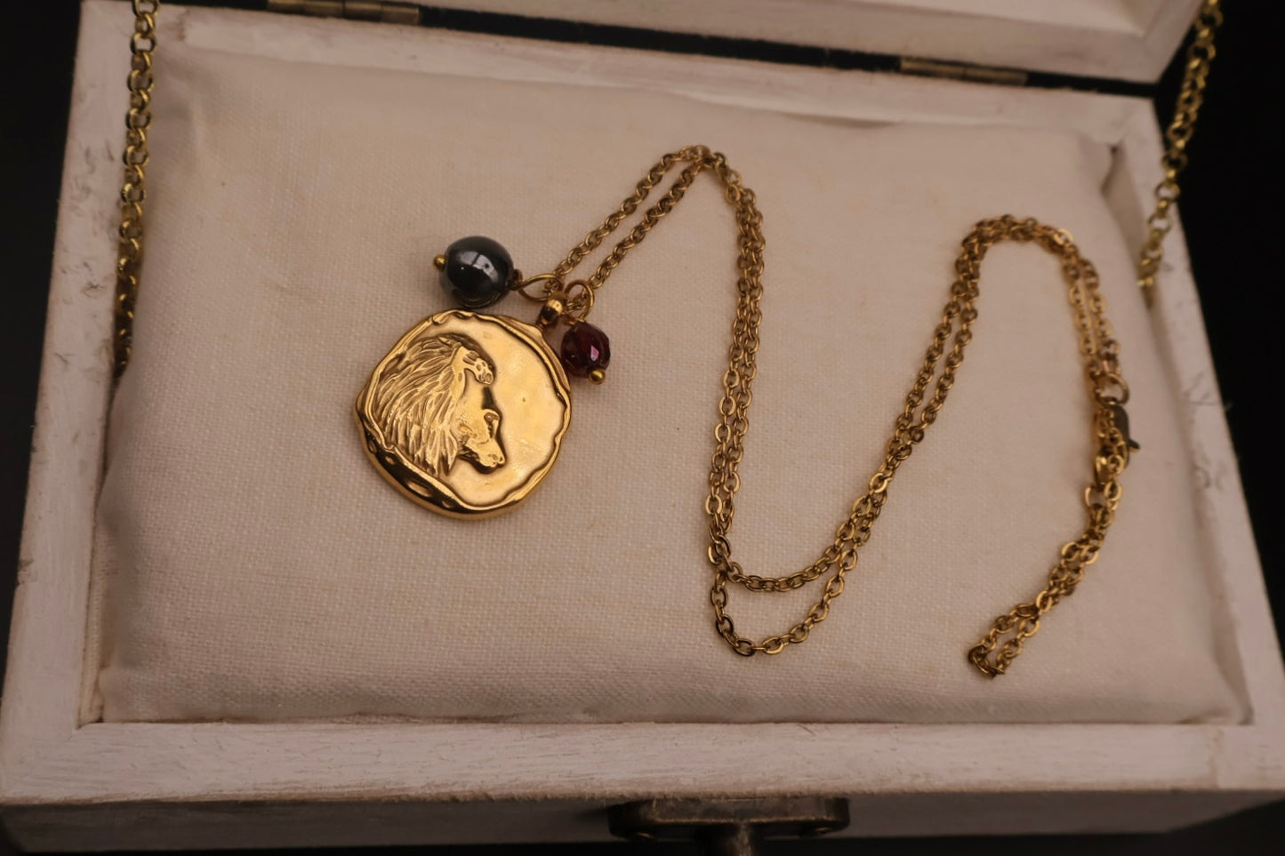 Gold necklace with a lion head pendant on a textured surface
