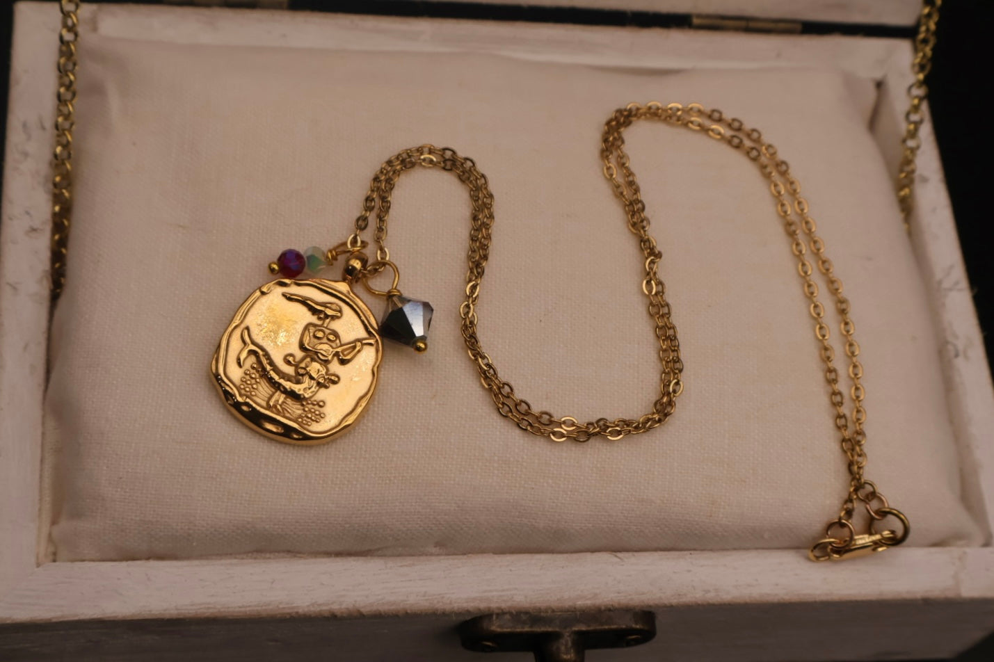 Gold necklace with a pendant on a textured surface