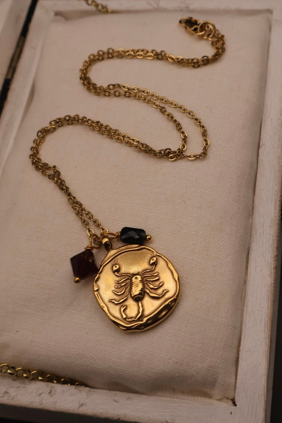 Gold necklace with a pendant on a white cushioned surface