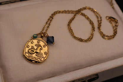 Gold necklace with a pendant on a beige surface