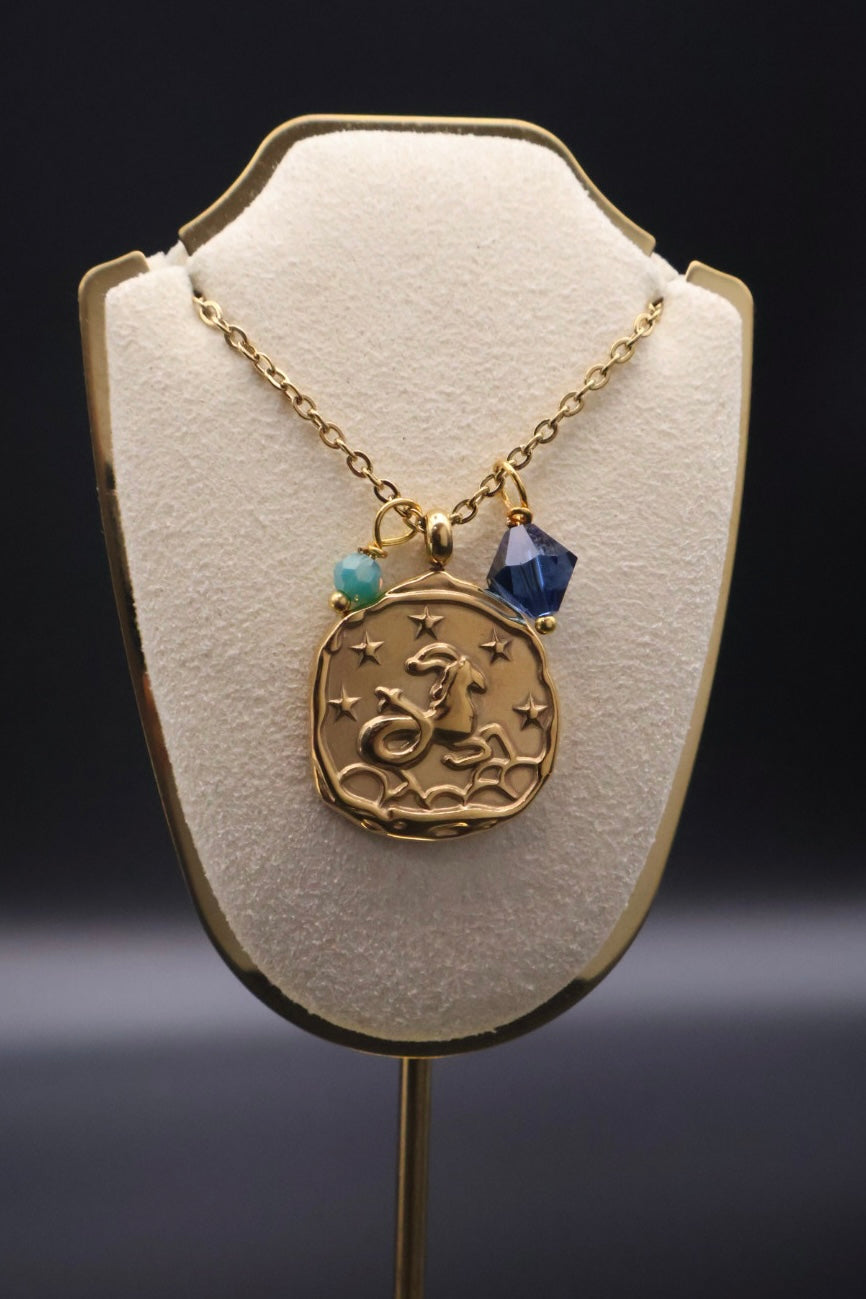 Gold necklace with a pendant on a white stand against a dark background