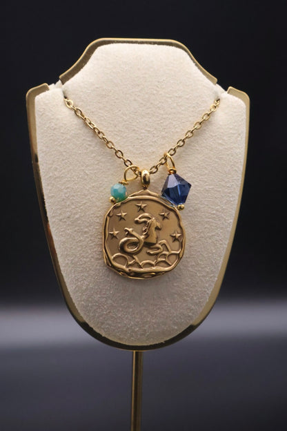 Gold necklace with a pendant on a white stand against a dark background
