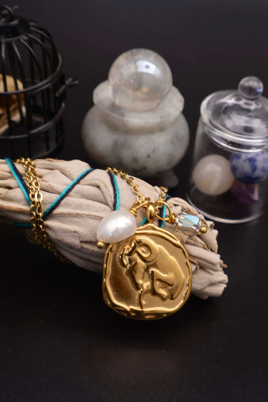 Gold necklace with a pendant on a dark surface with decorative items.