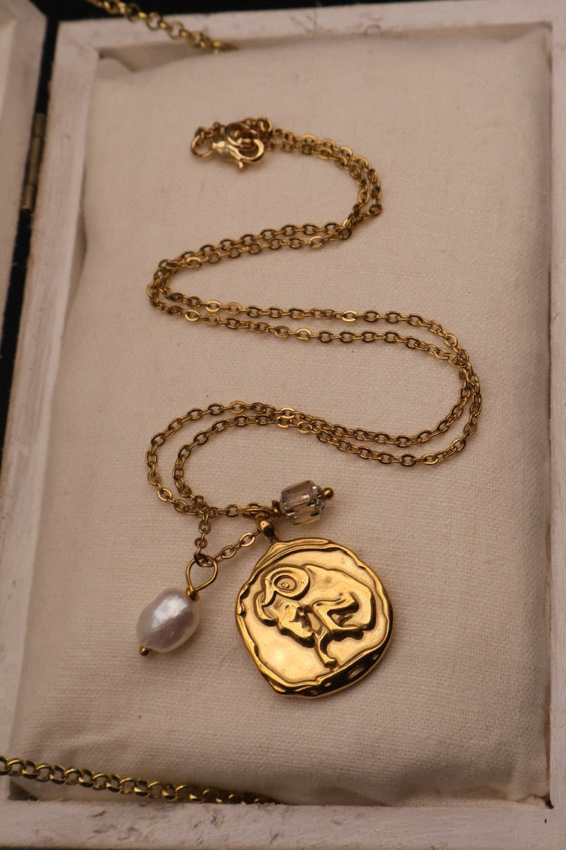 Gold necklace with a pendant in an open jewelry box on a dark background