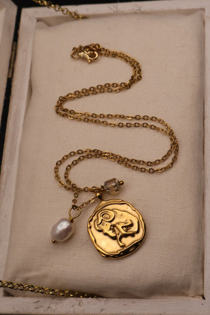 Gold necklace with a pendant in an open jewelry box on a dark background