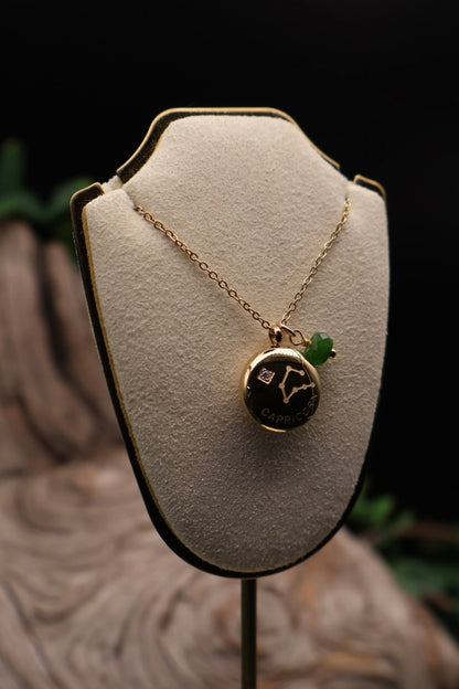 Gold necklace with a pendant on a white stand against a dark background