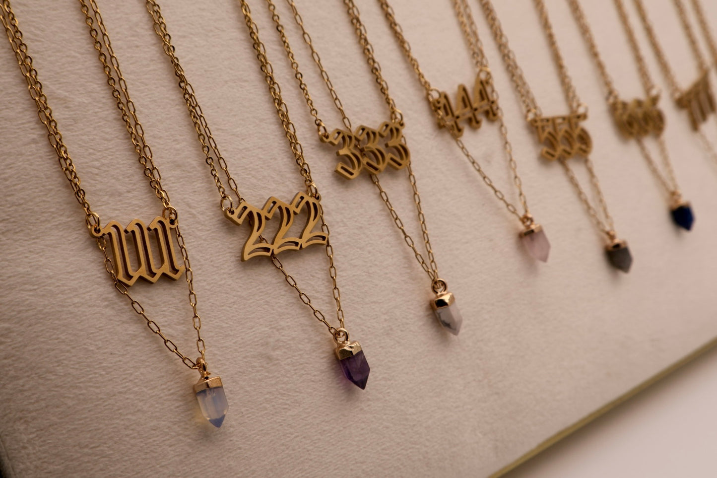 Gold necklaces with numbers and gemstones on a light background