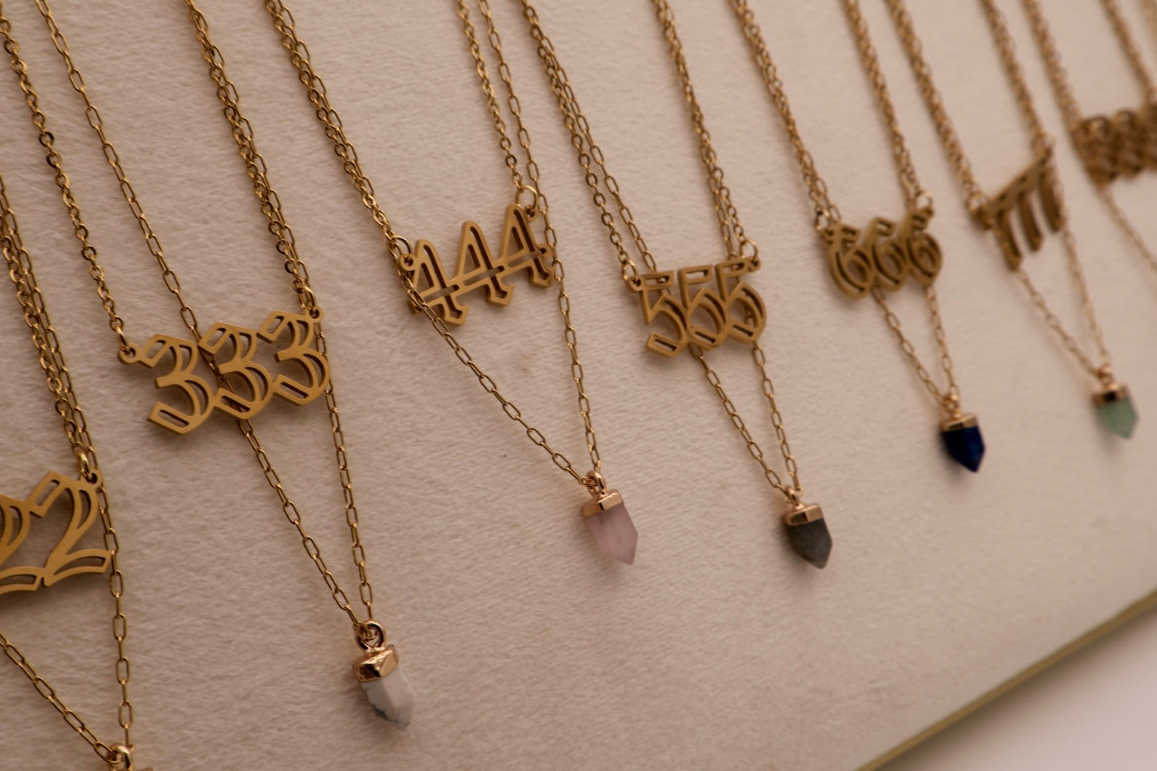 Gold necklaces with numbers and small stones on a light background